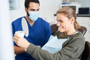 a dental patient smiles in a mirror